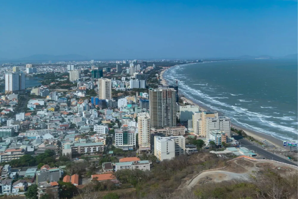 Vista aérea de diversos edifícios residenciais em bairros urbanos de Recife, com carros em ruas e algumas áreas verdes, simbolizando a densidade de ofertas de aluguel.